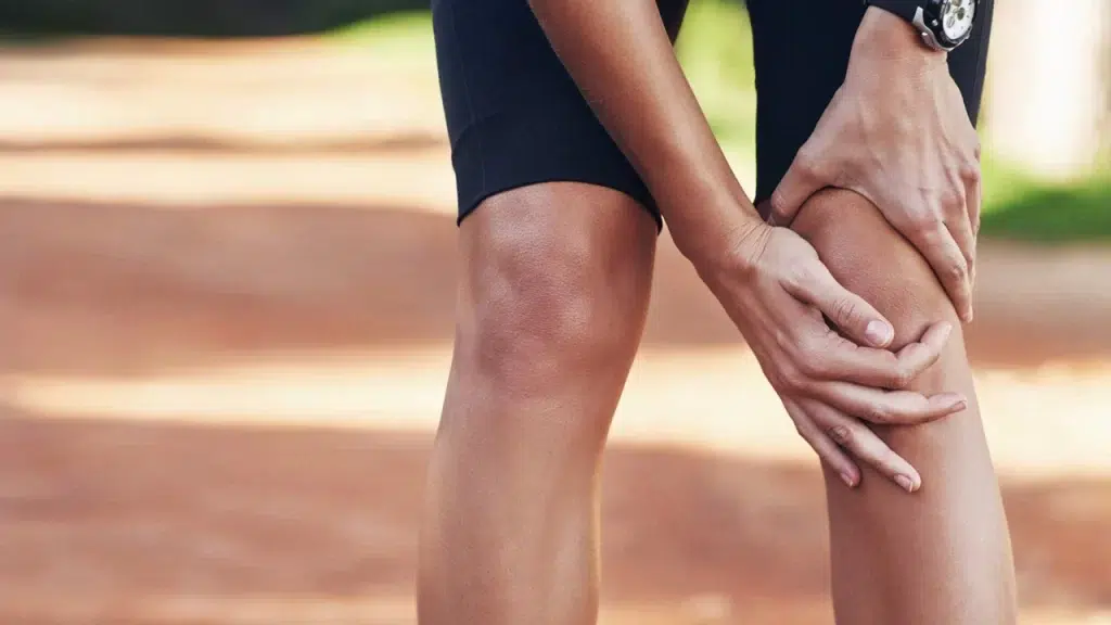 person holding knee having knee popping pain
